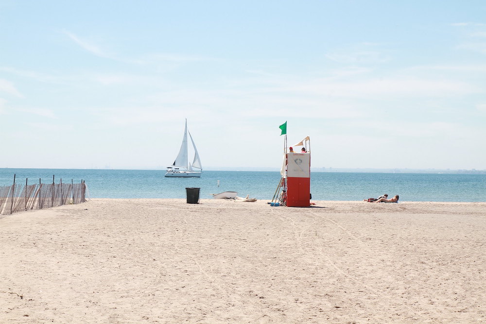 Looking for an incredible place to enjoy your next picnic in Toronto? This guide features some of the best picnic spots in Toronto from a local's perspective. Whether you're looking to picnic in a park, to spend your day sunning and snacking on a beach, prefer a garden hang, or want to check out a more unique destination, this guide has all of the best picnic spots for you to choose from. Pictured here: Hanlan's Point Beach
