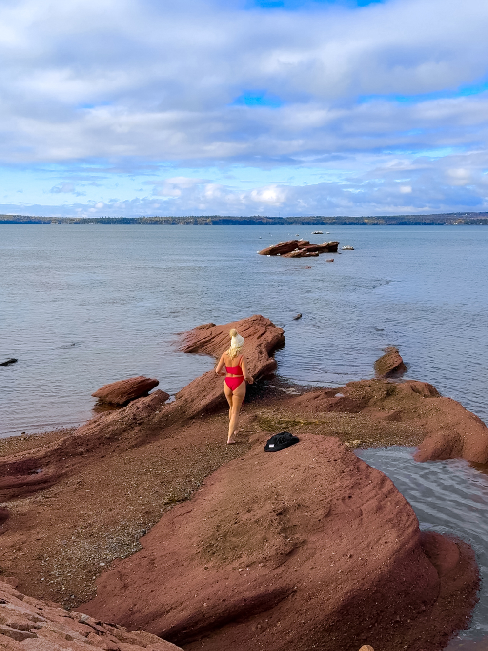Traveler experiencing a cold plunge in the Bay of Fundy near the Algonquin Resort, surrounded by scenic coastal views.
