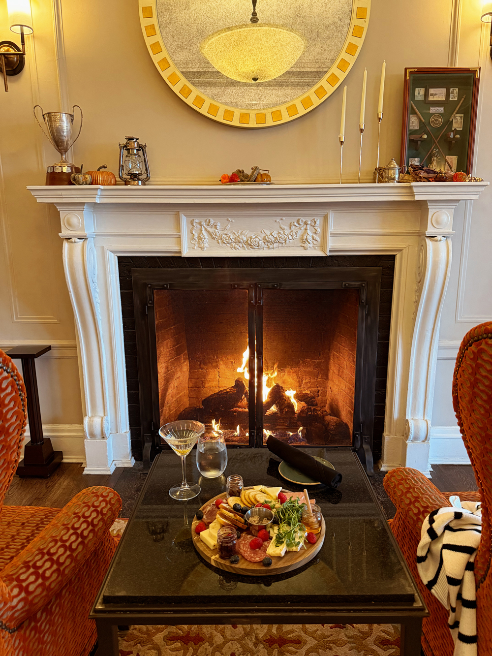 A cozy fireside set up at the Algonquin Resort with a charcuterie board and cocktail during a fall getaway.