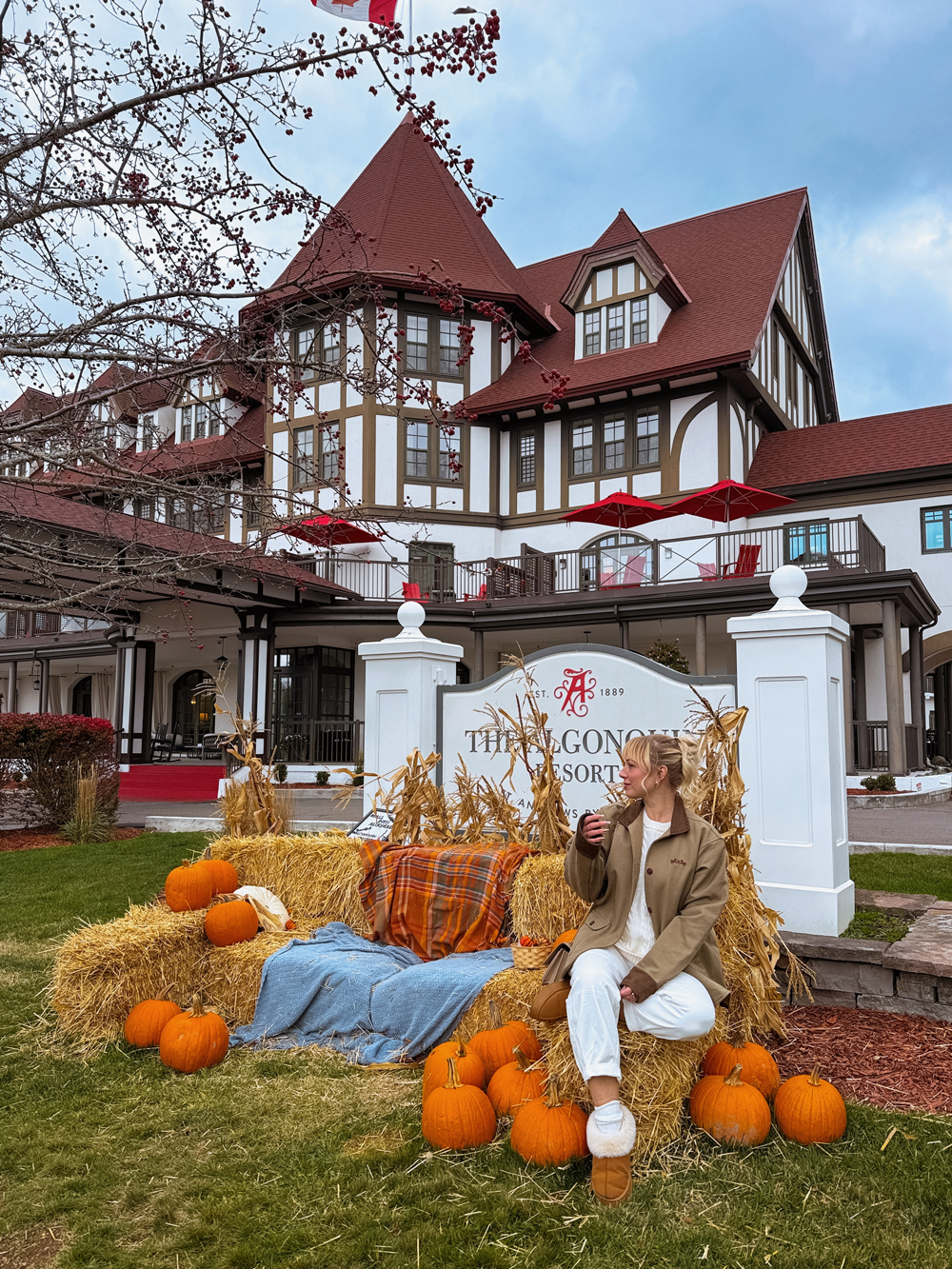 Woman enjoying a glass of wine surrounded by pumpkins and fall d&eacute;cor in front of the historic Algonquin Resort in St. Andrews by-the-Sea, New Brunswick