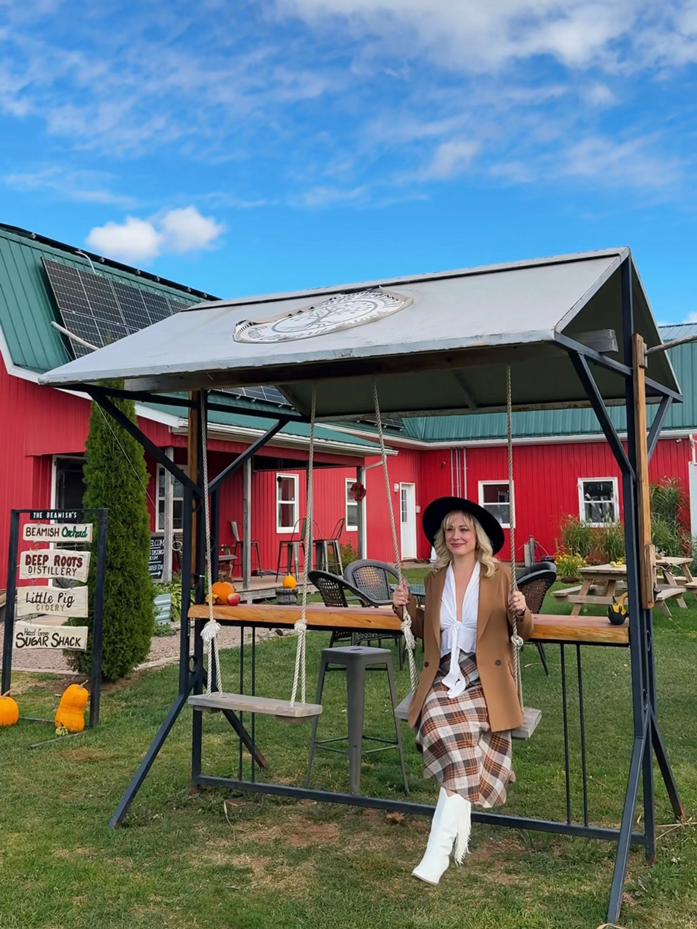 Woman on a swing at Deep Roots Distillery near Charlottetown, PEI, during fall.