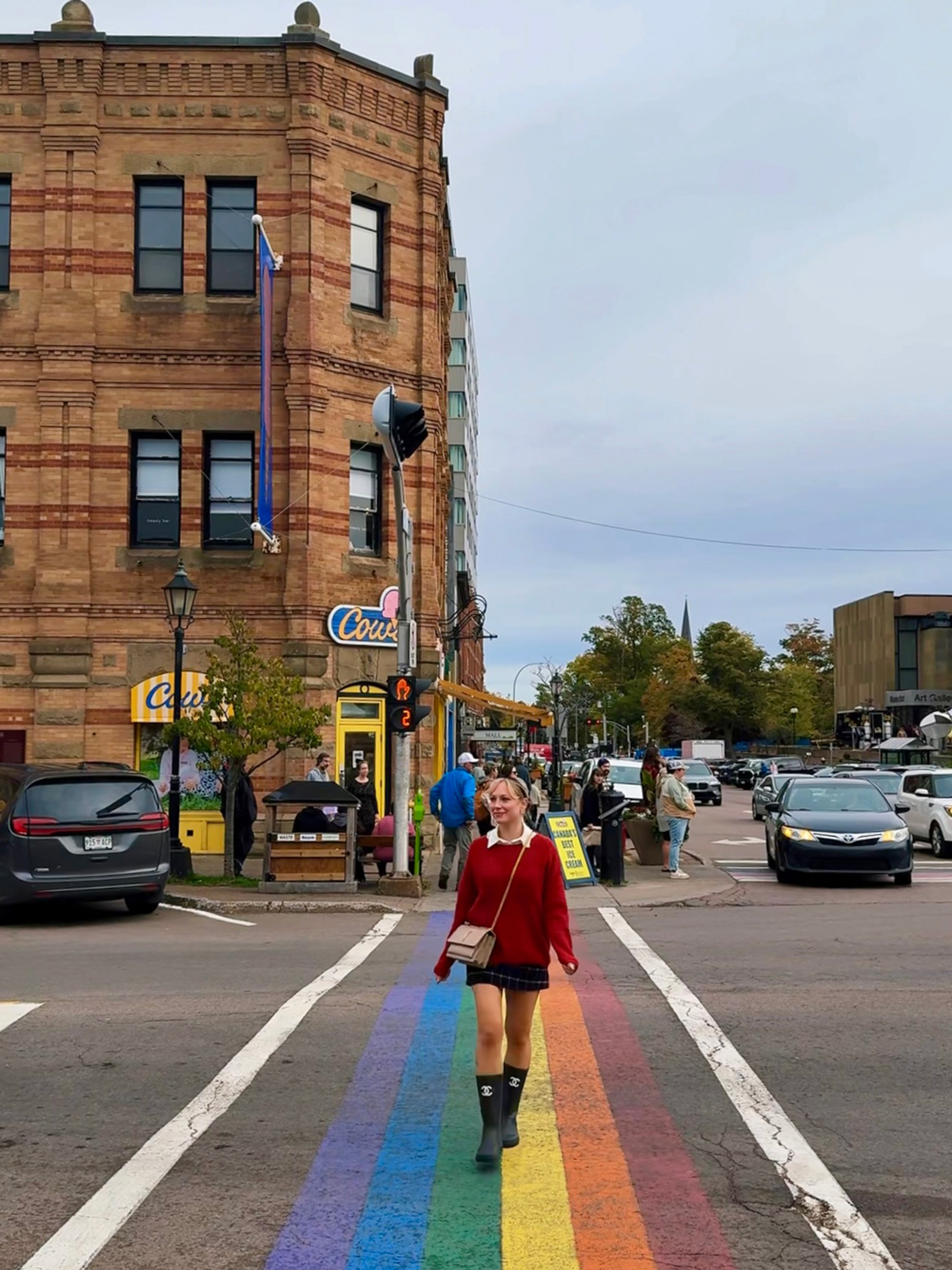 Exploring downtown Charlottetown, PEI in the fall &mdash; woman walking along the rainbow crosswalk surrounded by historic buildings and local shops.