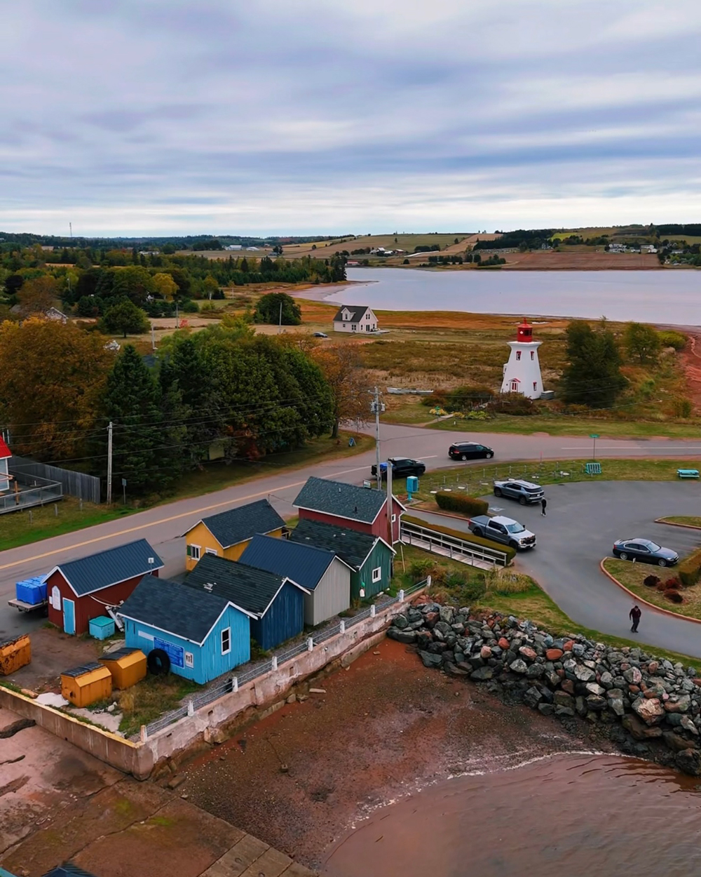 Aerial view of Victoria-by-the-Sea, Prince Edward Island &mdash; colorful cottages, lighthouse, and shoreline in autumn.
