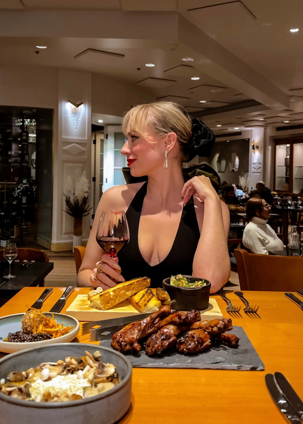 woman dressed for an elegant night out enjoying a gourmet dinner and a glass of wine at Nymark restaurant.