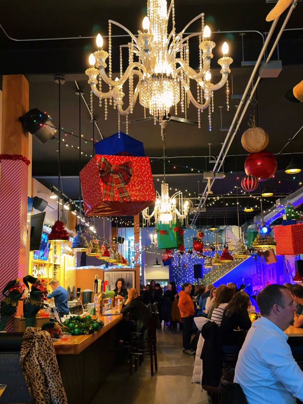 Bar interior decorated with oversized hanging presents, chandeliers, and holiday lights at The Block Public House in North Bay.