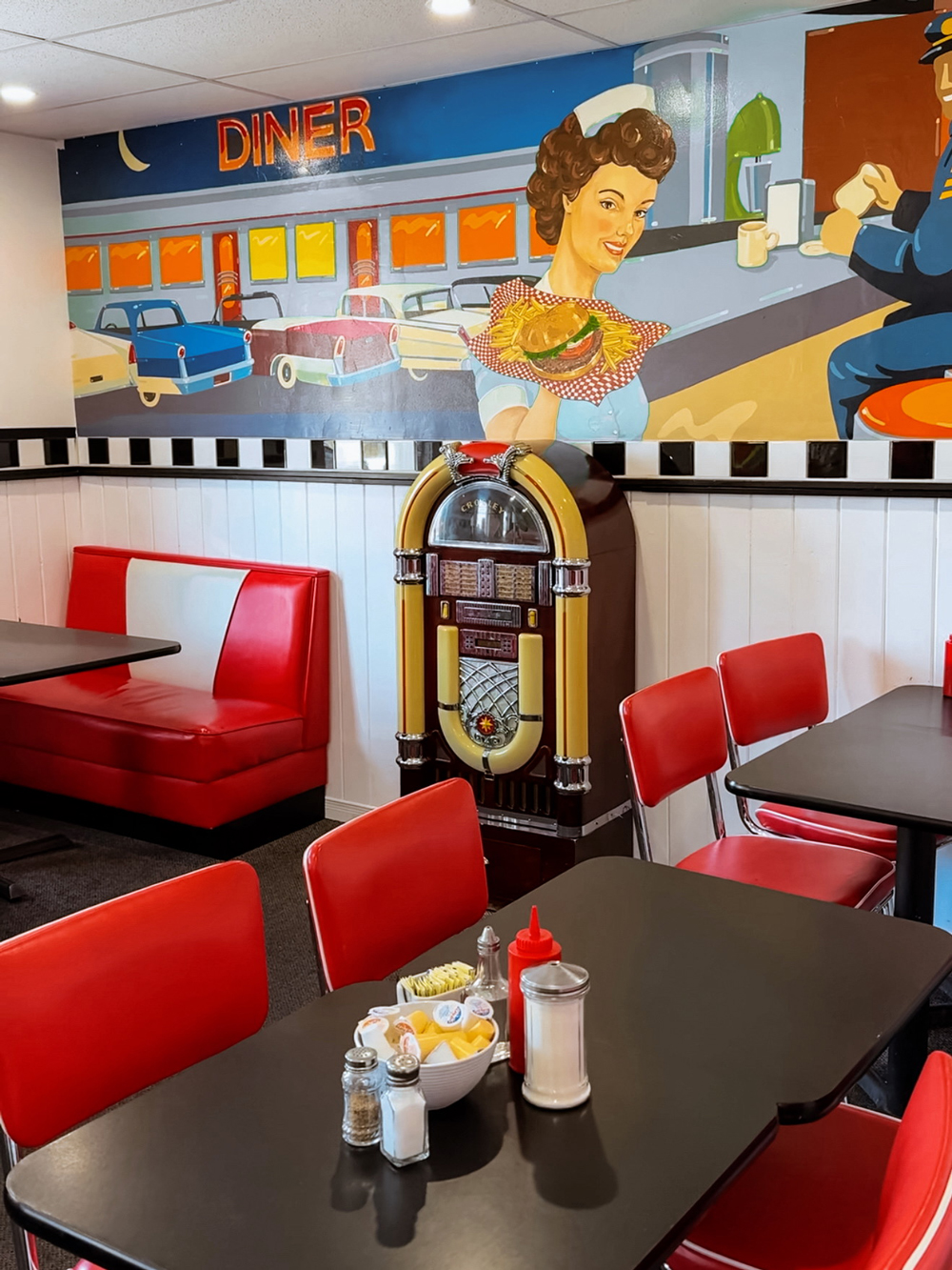 Retro-style diner interior with red booths, a jukebox, and a colourful mural at Hoagie&rsquo;s Diner in North Bay.