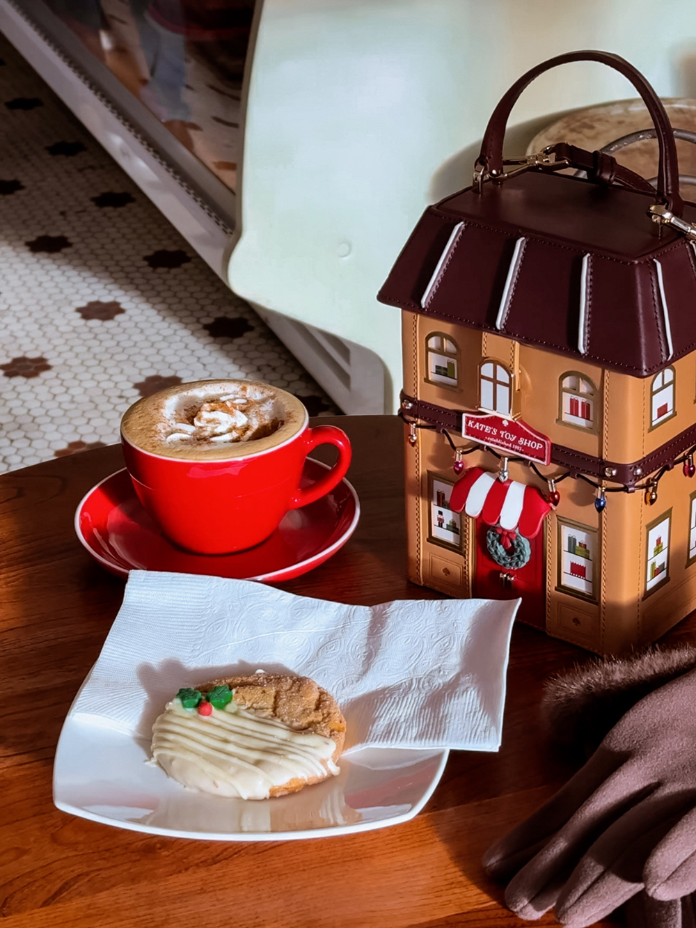Holiday latte and iced cookie on a table with a Christmas toy shop shaped purse at Opera Bakery Caf&eacute;.