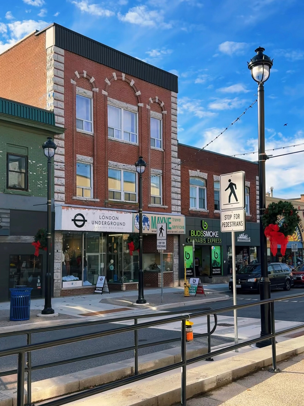 Street view of downtown North Bay with brick buildings, storefronts, and holiday decorations.