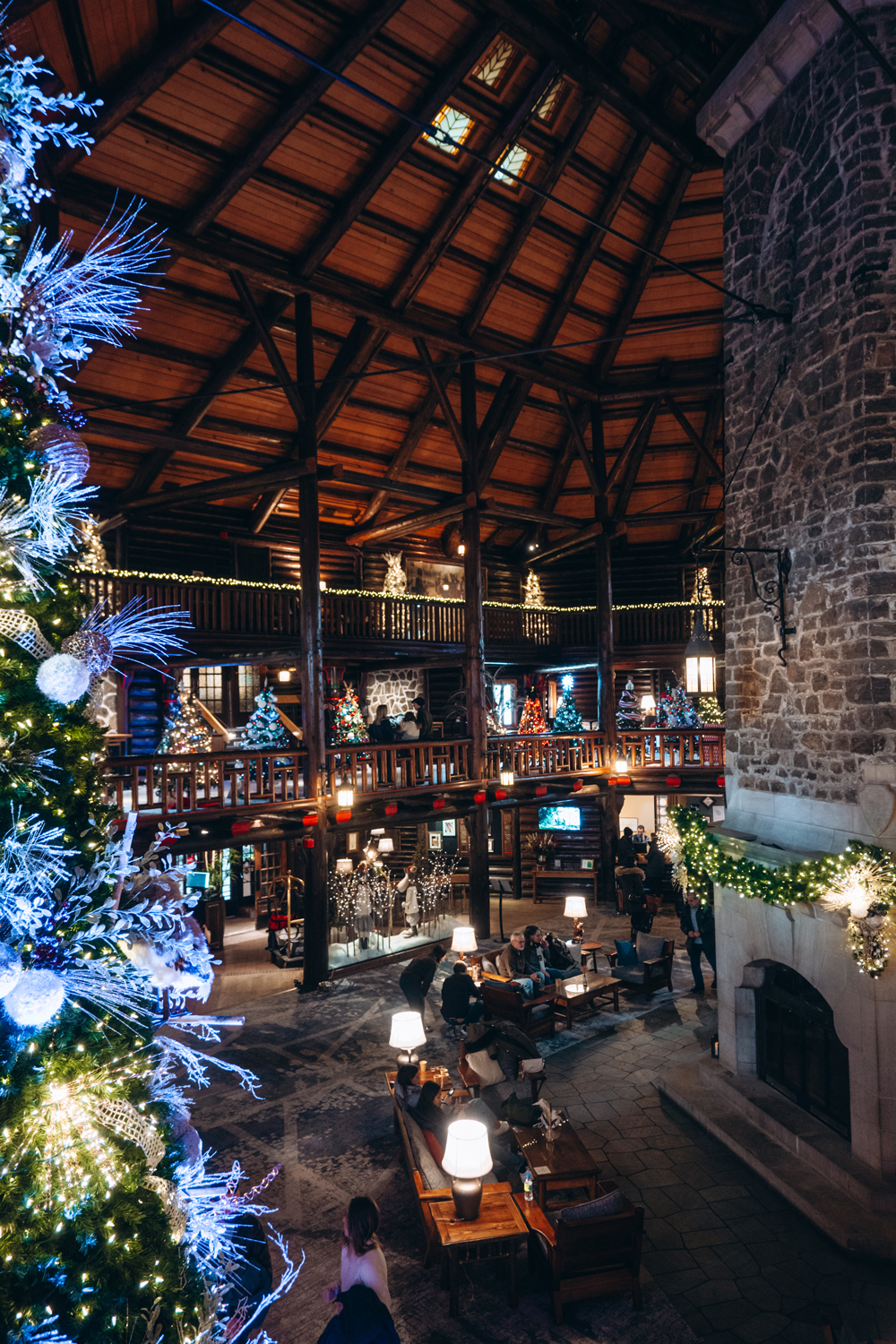 Holiday decorations inside the grand lobby of Fairmont Le Ch&acirc;teau Montebello, featuring a large Christmas tree, garlands, and the iconic log-cabin architecture.
